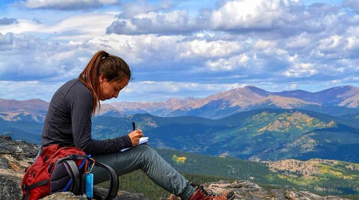 A hiker resting on a summit above Idaho Springs, the Front Range behind